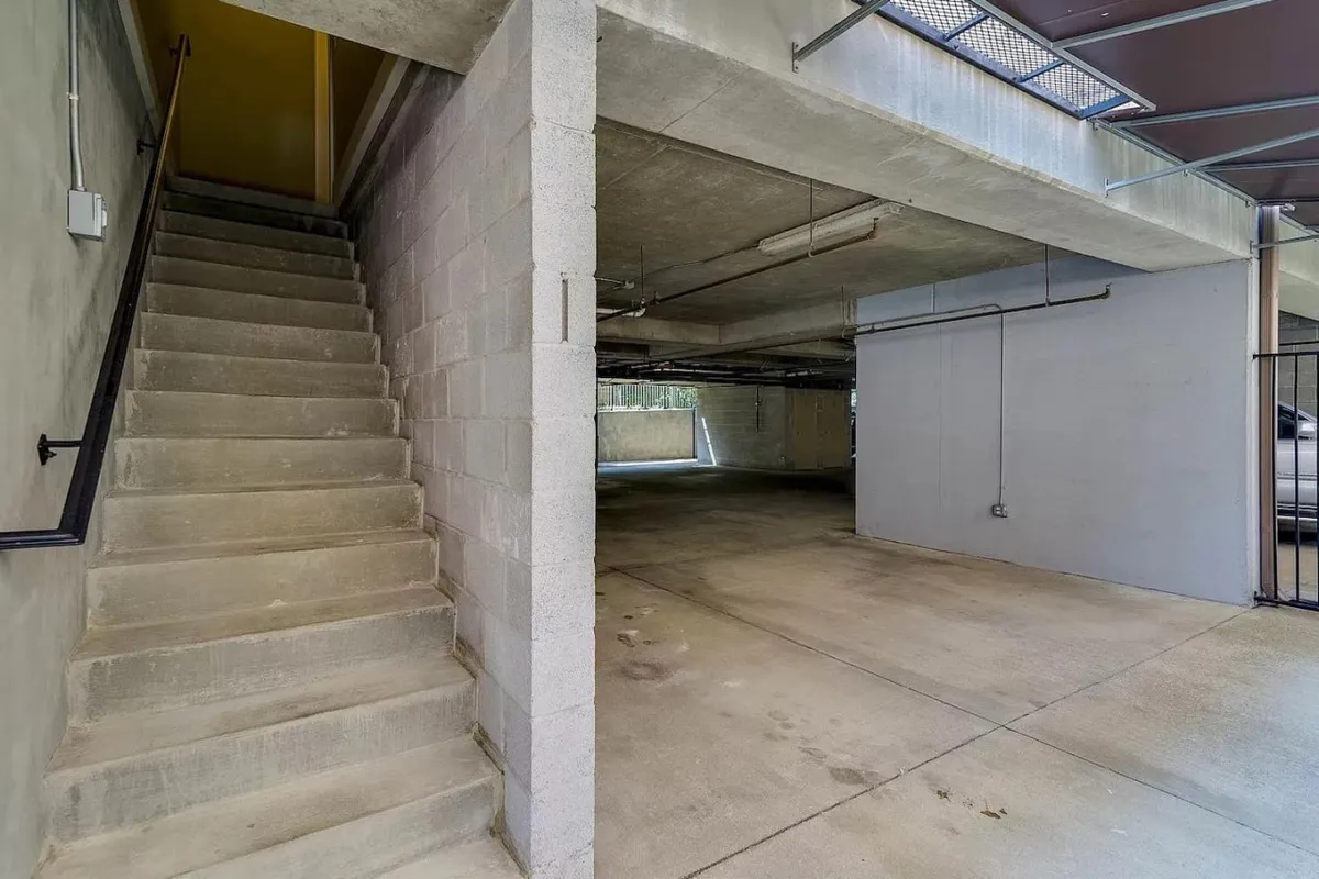 This image captures a staircase leading up from an open parking area, blending a transition between indoor and outdoor environments. The view highlights the convenient parking arrangement and the immediate access to the home's living spaces, hinting at the ease of arrival and group comings and goings.